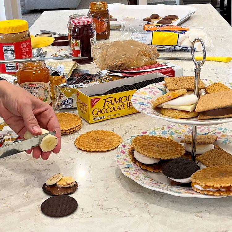 Image shows a counter covered in different cookies and chocolates to make Smores for a Smores bar.