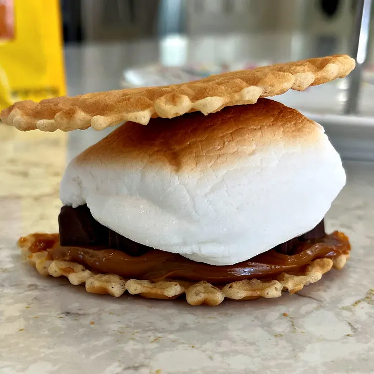 This crunchy vanilla waffle cookie makes the most delicious Smores when topped with a thick layer of Dulce De Leche, Chocolate Dulce De Leche truffles, and a jumbo roasted marshmallow.