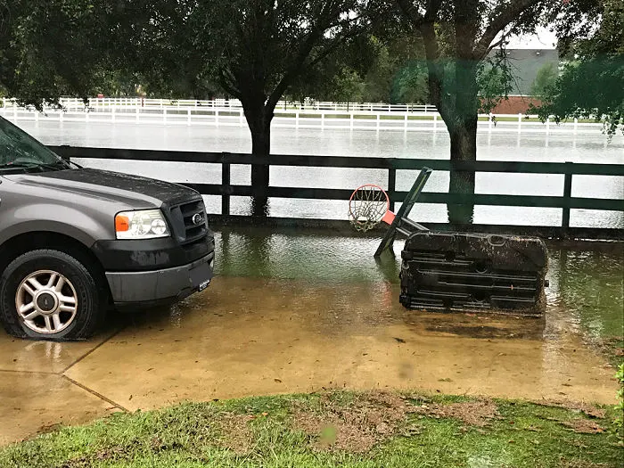 Image of flooding in a driveway with a truck and basketball hoop.