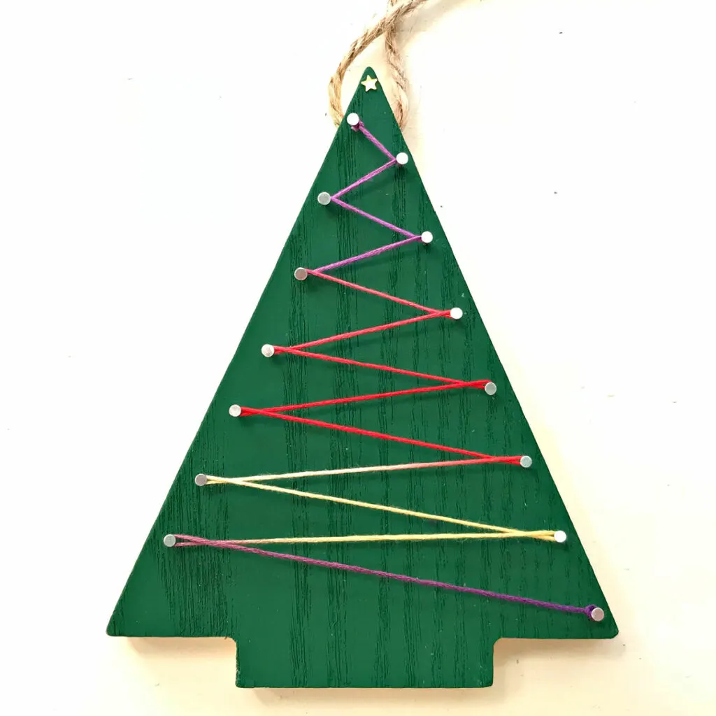 Image of a wooden Christmas Tree ornament with embroidery floss string art.