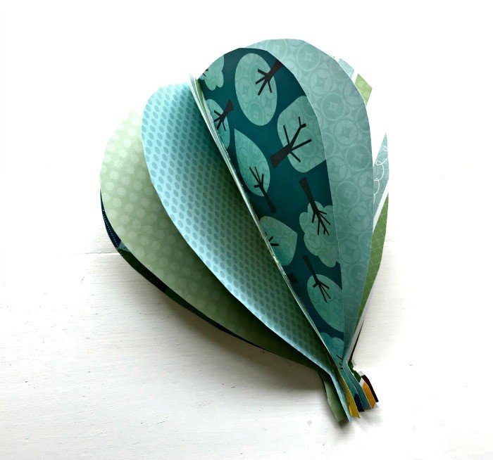 One 3D paper hot air balloon craft on a white background. Learn How to Make Paper Hot Air Balloon Wall Art with cute double-sided scrap book paper. This tutorial is easy and works great on walls or as a mobile in a kid's room.