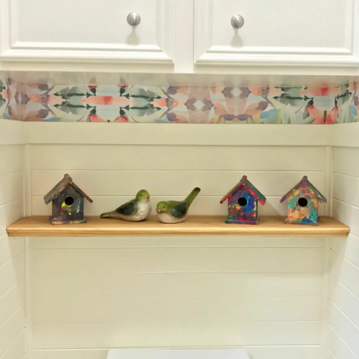Image of a simple DIY wood shelf over a toilet in a small bathroom.