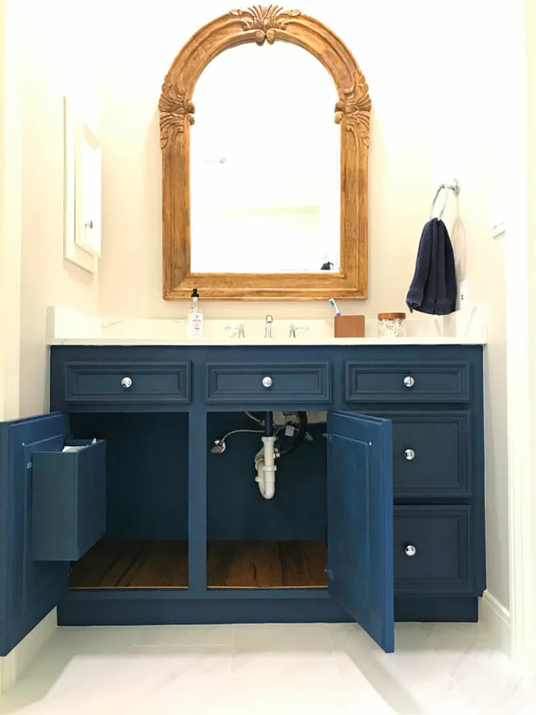 DIY hanging trash can inside cabinet door of a bathroom vanity.