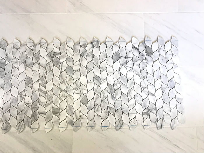 Marble Mosaic Tile marked with cut lines on the floor of a bathroom.