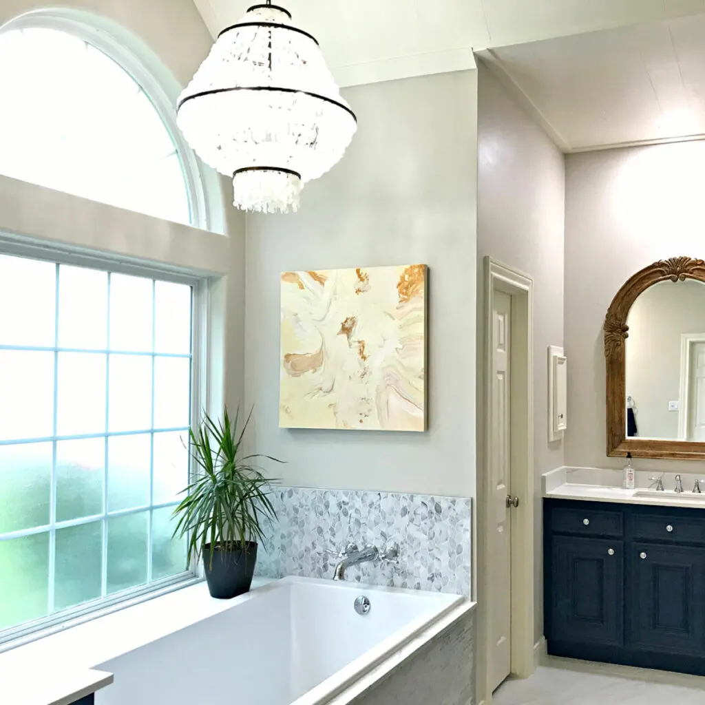 White marble master bathroom with blue cabinets and light walls.