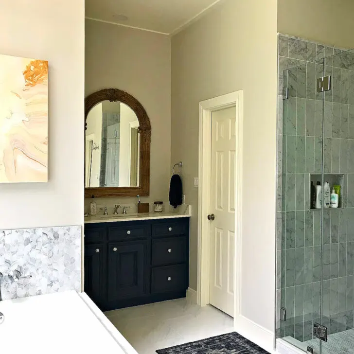 White Marble tile and floor in a Master Bathroom with dark blue vanities after a Before and After Master Bathroom Remodel.