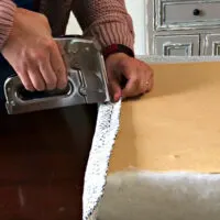 Image of someone using a staple gun to upholster a board to make a boat or bench seat cushion.