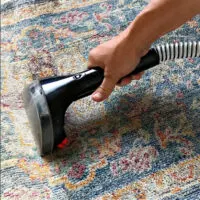 Image of someone showing how to clean area rugs at home using a Bissell carpet cleaner.
