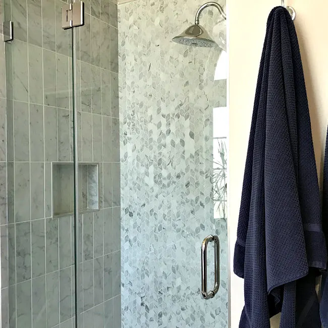 You can quickly and safely clean a shower glass door with marble or stone tile using vinegar & backing soda. But, be careful doing it! Vinegar can etch, stain, and pit your marble and stone tile. Here's a step by step guide to how to clean your glass shower door without damaging your tile.