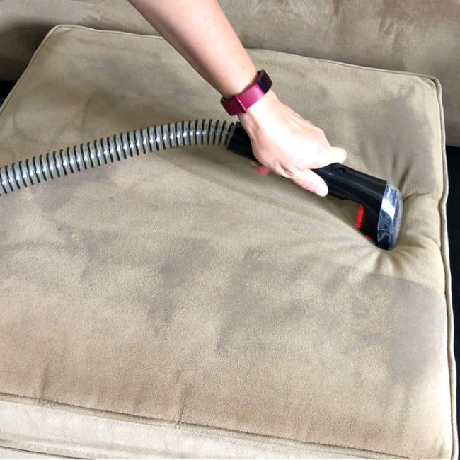 Cleaning a couch with a Bissell and the approved cleaner.