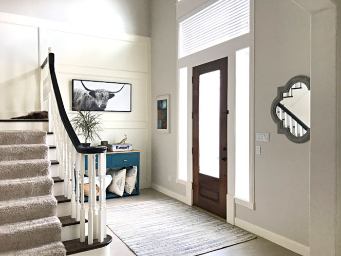 View of a stained wood door in a white 2 story entry of a home.