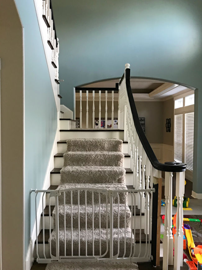 Before photo on a foyer makeover. Foyer has blue paint and a baby gate on the stairs.