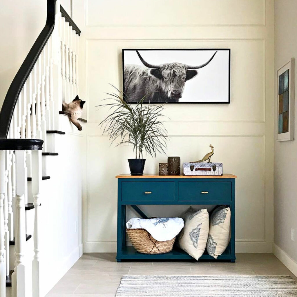 White trim molding finish carpentry in a large foyer with stairs with a black railing.