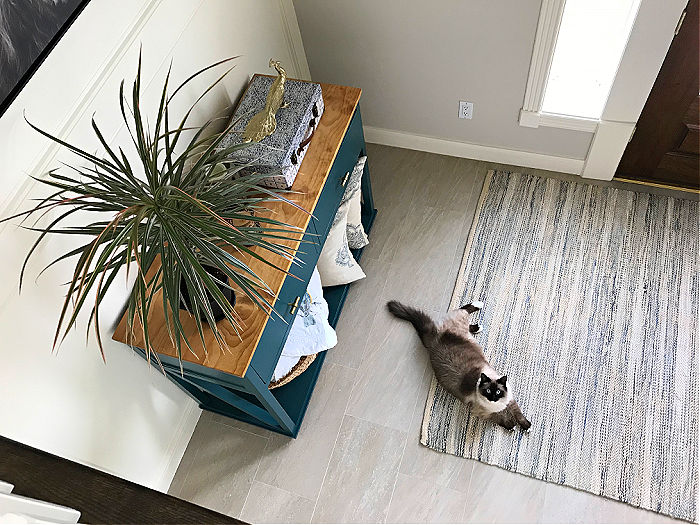 White foyer from above with light tile floors and a natural fiber tan and blue rug.