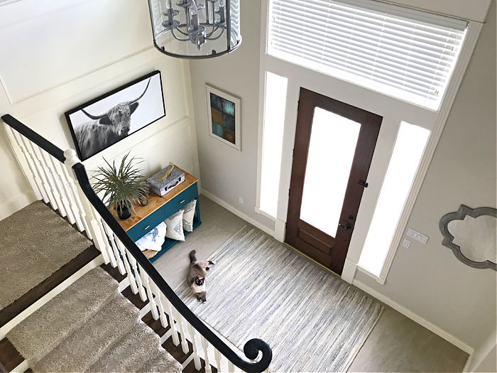 Image of a traditional white home entryway. Looking down from the 2nd floor of a landing that overlooks the foyer in a home.