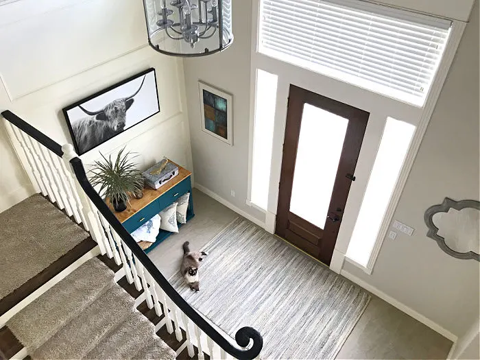 Image of a traditional white home entryway. Looking down from the 2nd floor of a landing that overlooks the foyer in a home.