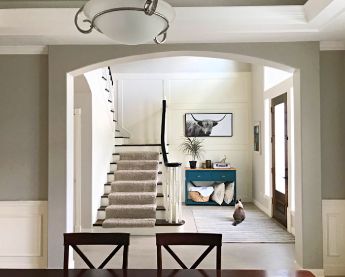 View through an archway of a white foyer with board and batten walls.