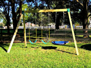 Assembled Swing Set made with Pressure Treated Lumber with 3 swings hanging from it.