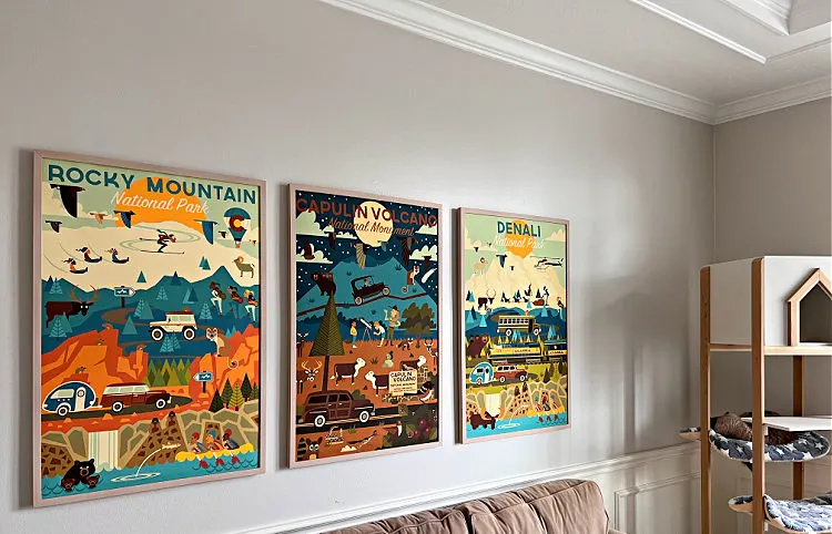 Set of 3 vintage travel posters framed over a couch.