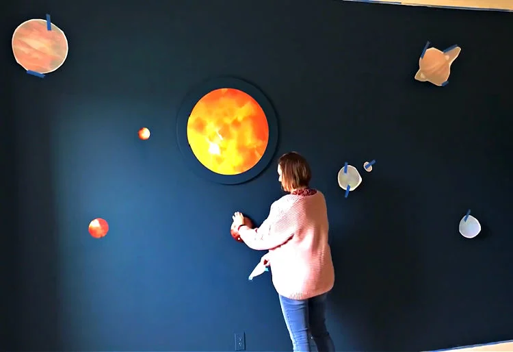 Image of vinyl stickers of planets and a sun on a wall.