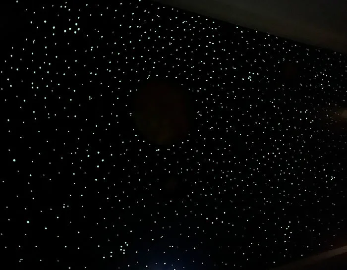 Image of a kids bedroom wall, at night, decorated with glow in the dark stars.