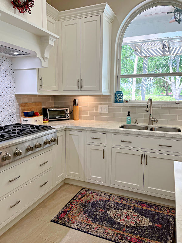 Image of a kitchen with white inset cabinets, Lusso Quartz, undermount sink, with a gas grill stove. 