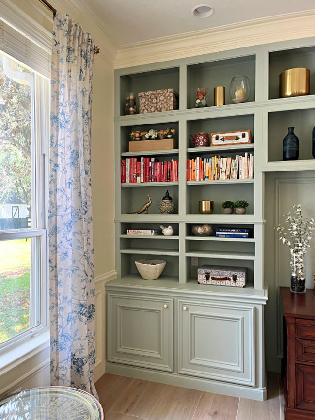 Photo of light green cabinets after a DIY home office remodel. With blue and white curtains next to a window.