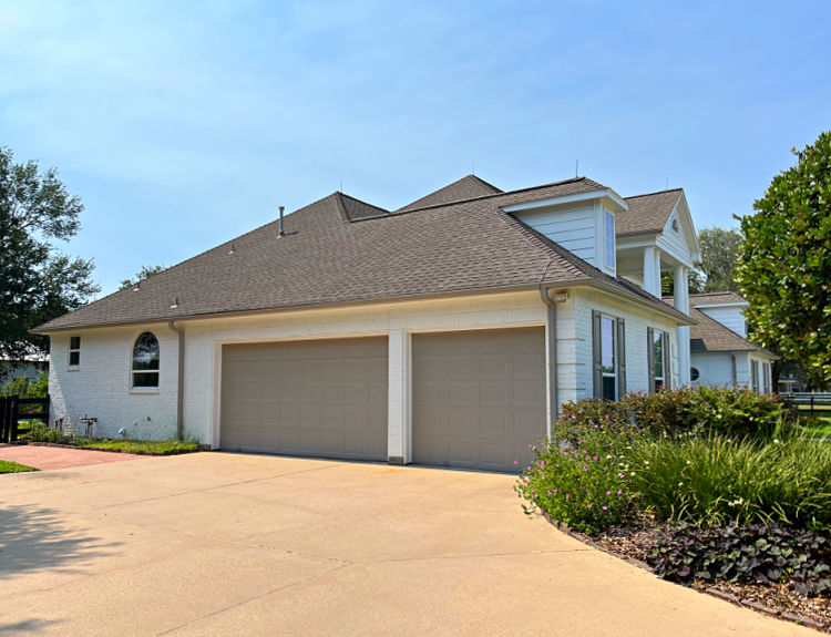 White brick house with grey garage doors and gutters.