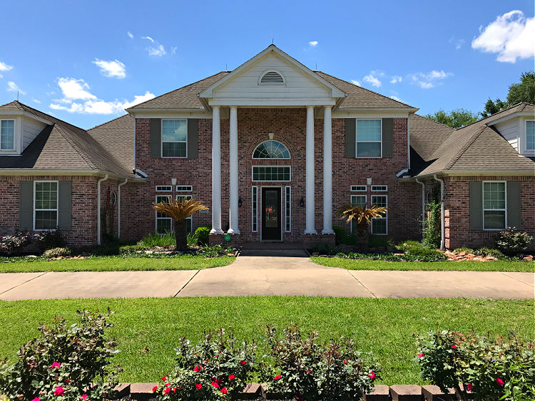 Before picture of a 2-story brick house with 2 story columns in front.