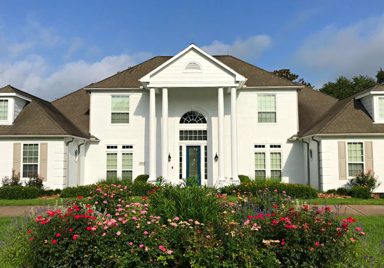 After image of a 2-story brick house painted white with Sherwin Williams Loxon XP.