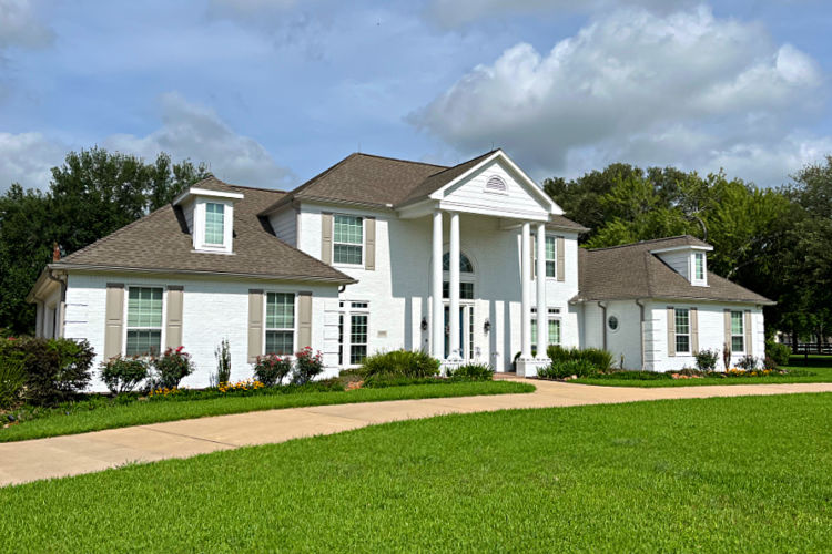 Large white brick house with columns.