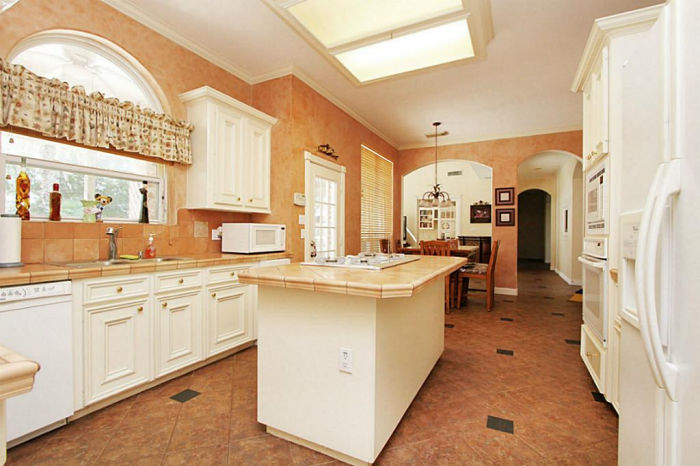 Image of a 1990's kitchen with orange tile floor and tile counters.