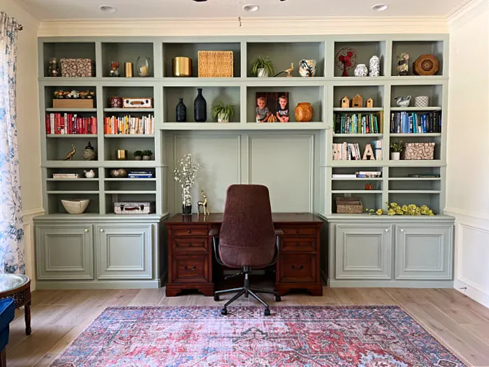 Large, organized home office with green storage cabinets and shelves with white walls and trim. And, organized office shelves with nice decorations.