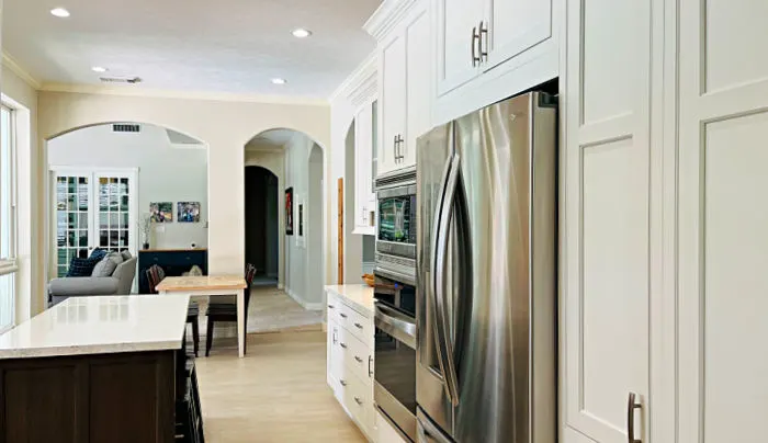 Image of white kitchen cabinets and pantry with stainless steel appliances.
