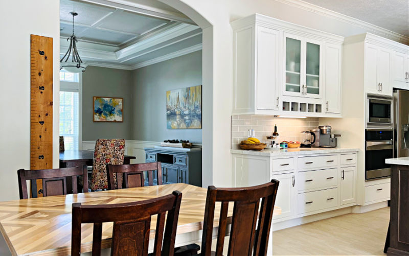 Image of a Dining Room seen through a large white kitchen.