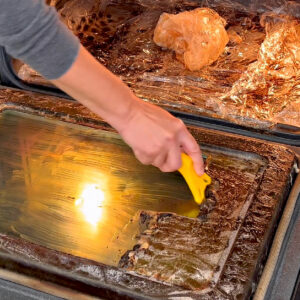 Image of someone using Easy Off Oven Cleaner Fume Free on oven glass door with a razor.