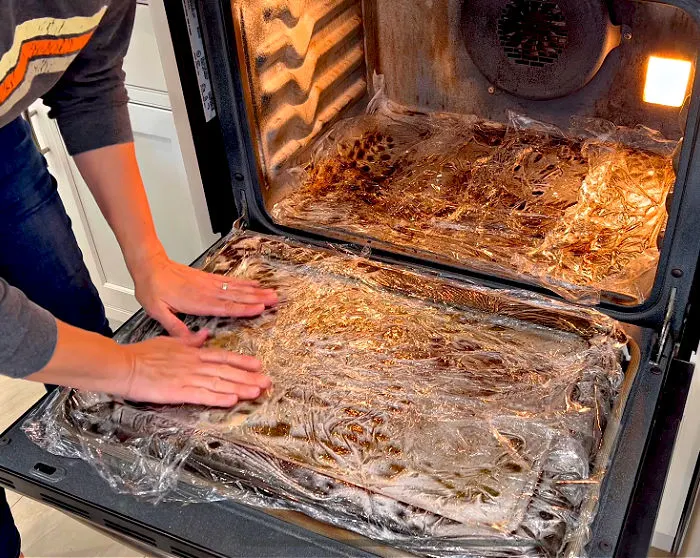 Image of Oven Cleaner covered with plastic wrap to clean a dirty oven.
