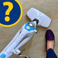 Image of someone using a steam mop on tile floors in a post about if steam mops are safe on tile, linoleum, vinyl, engineered hardwood, hardwood, and marble.