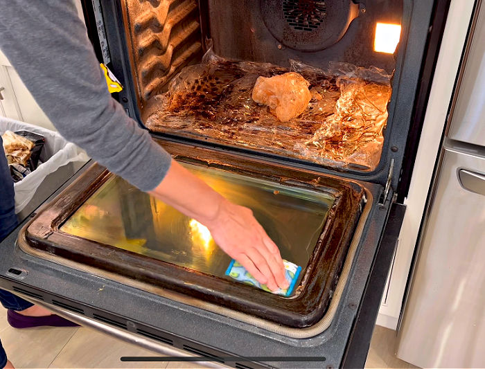 Scrubbing an oven with a scour daddy scrub daddy sponge.