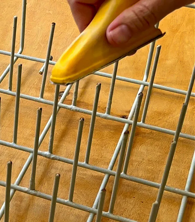 Image of someone sanding the rust on a dishwasher rack.