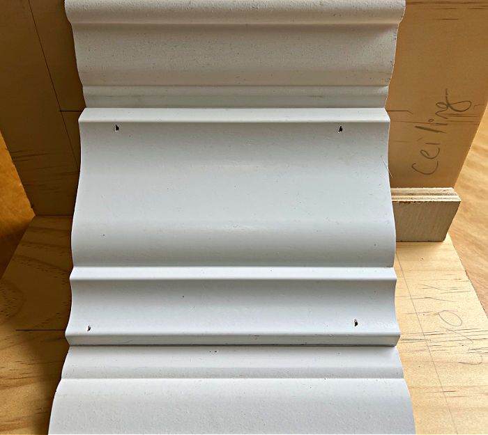 Image shows 3-piece crown molding sample with brad nail holes.