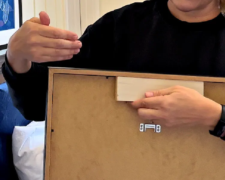 Image shows a wood block being used to hang an IKEA Ribba Picture Frame.