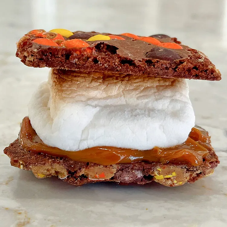 This cool Smores idea is a Reese's Pieces Brownie Brittle Smores with Dulce De Leche and Toasted Marshmallow. 