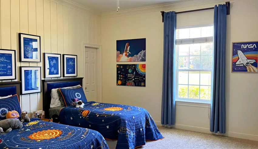 White walls kids bedroom for boys with blue velvet curtains, dark blue space themed bedroom quilts and NASA and cool outer space decor and wall art.