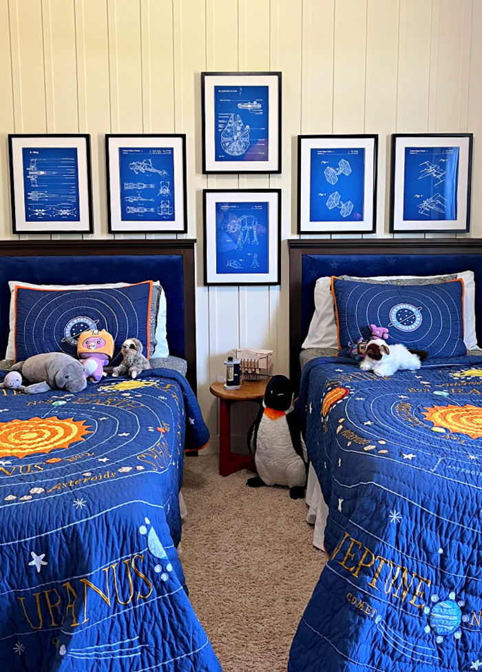 Pottery Barn Outer Space Solar System quilts on 2 twin beds with Star Wars blueprint art above the beds.