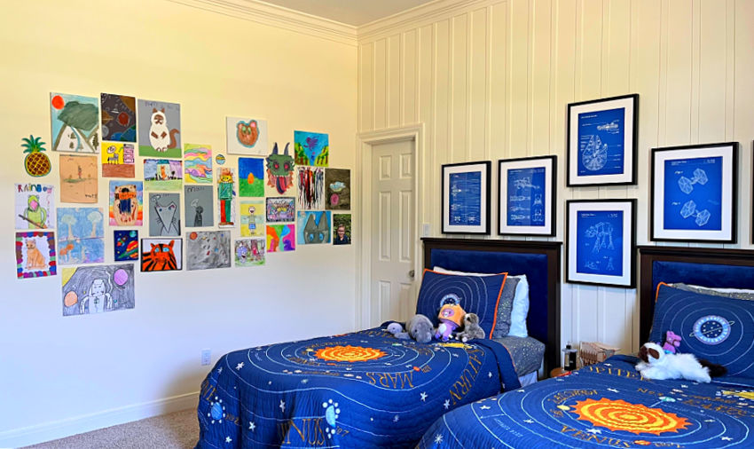 Kids artwork displayed on a white wall in a boys bedroom with a space theme and blue solar system bedding!