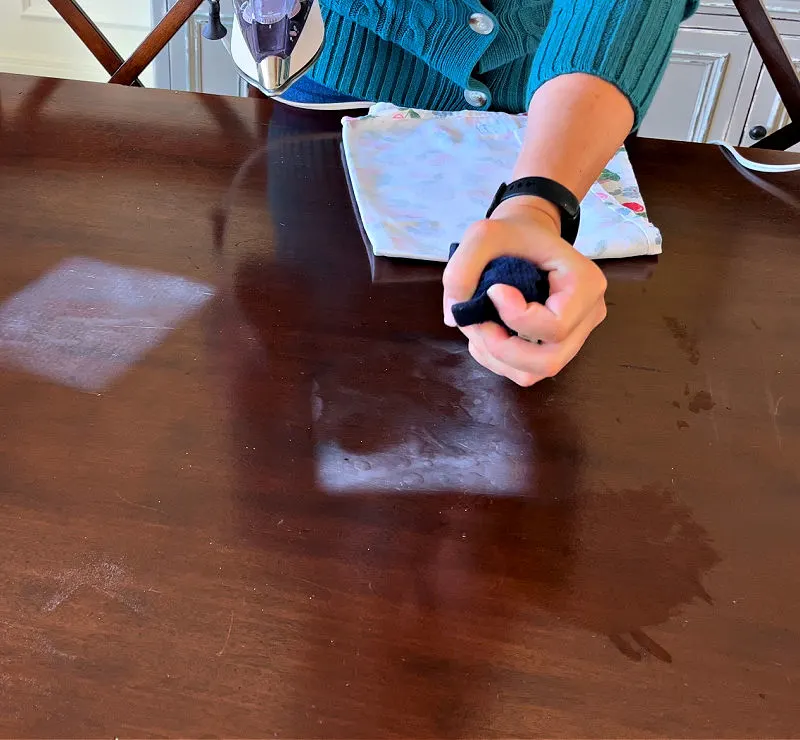 Using a steam iron to remove a white heat mark on a wood table.