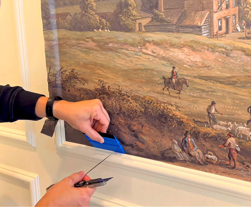 How to use a utility knife to trim the edges of a framed wallpaper mural DIY.