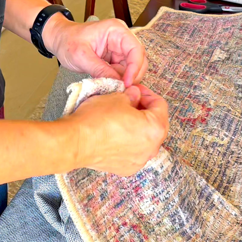 I use a curved upholstery needle and thread to sew under the top and bottom borders on a rug.