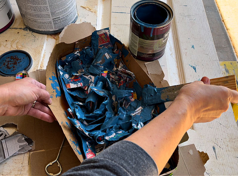 Newspaper mixed with paint to dry out paint for disposal.